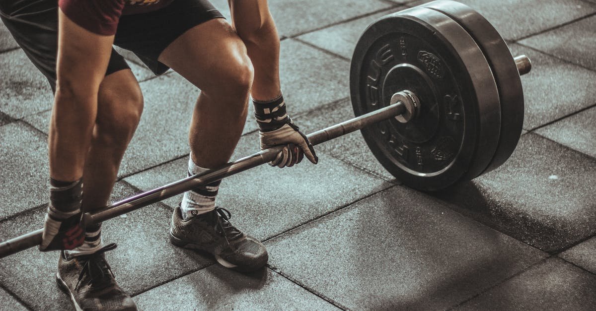 A focused weightlifter prepares to lift a heavy barbell in an indoor gym setting.