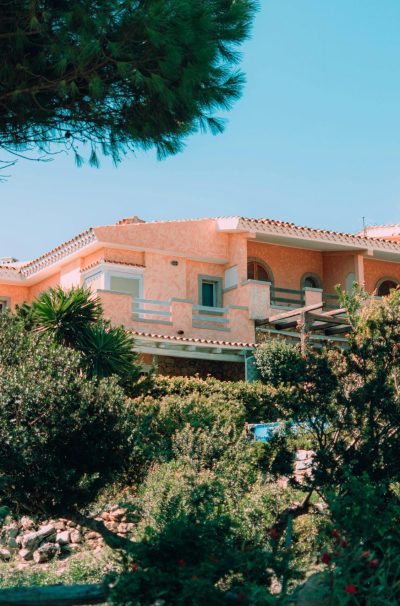 Charming Mediterranean villa nestled in vibrant, lush gardens under a clear blue sky.