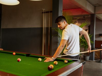 Man focused on playing snooker in a stylish indoor club environment.