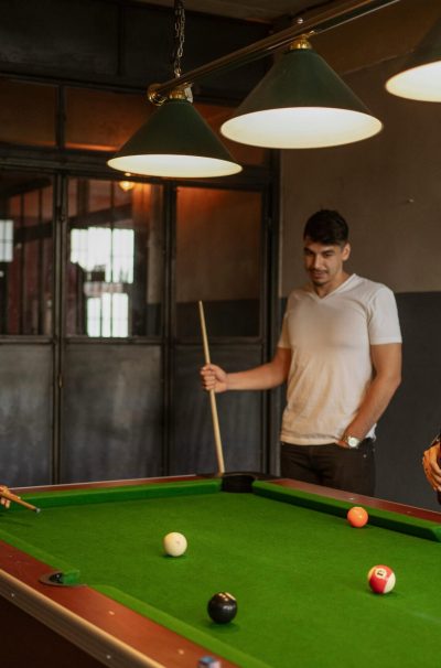 Three friends playing billiards at a club, enjoying leisure time and camaraderie indoors.