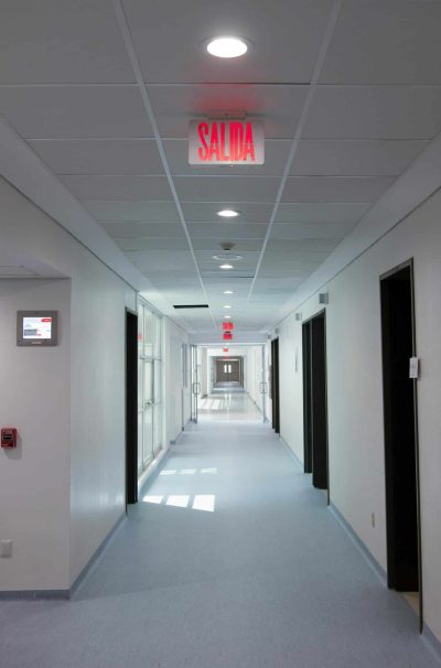 Empty hospital corridor with 'Salida' exit sign, featuring clean design and bright lighting.