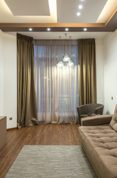 A sleek beige living room featuring a flat screen TV, sofa, and elegant lighting.